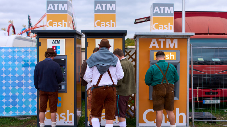 Men dressed in traditional lederhosen stop at ATMs to grab cash