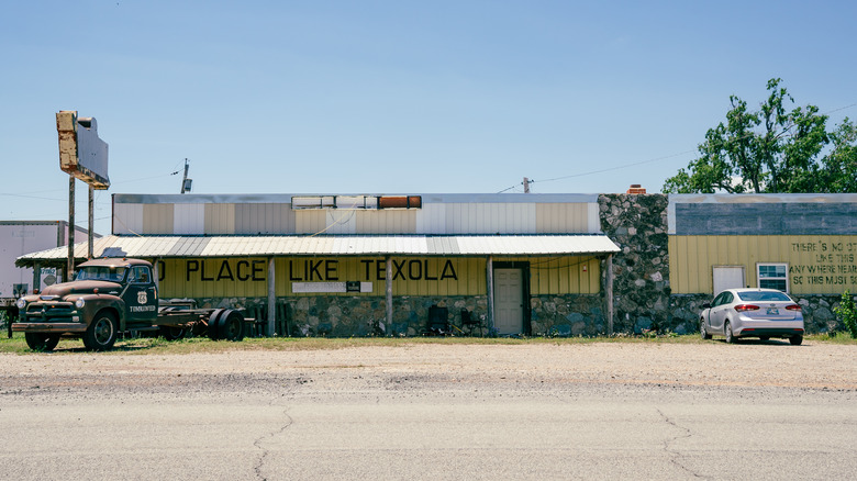 An abandoned building with "No Place Like Texola" written on the exterior