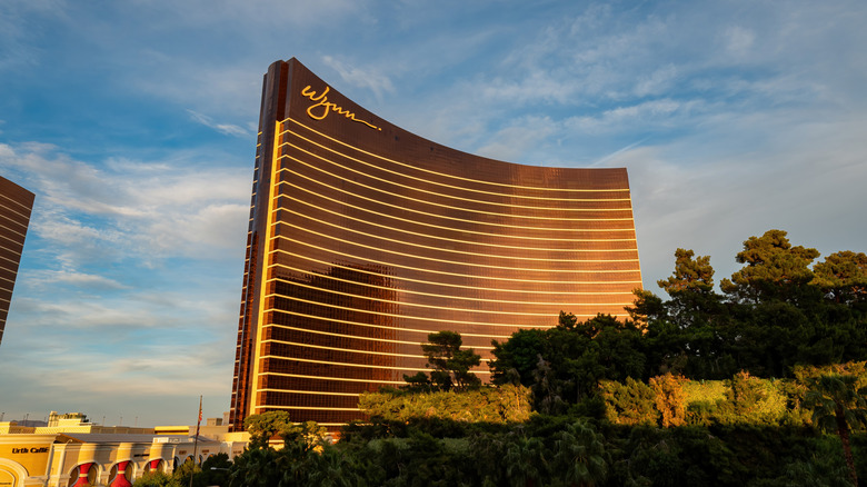 Wynn Las Vegas glowing at sunset, its curved bronze tower reflecting the evening sky