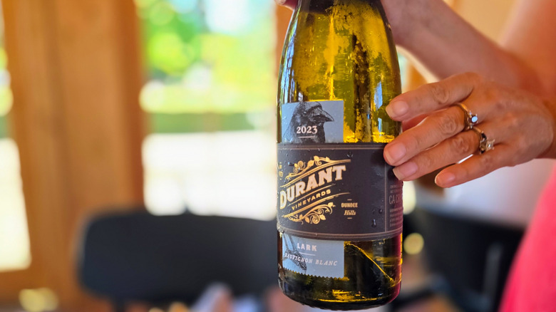 A person holding a Durant Vineyards white wine inside of the estate