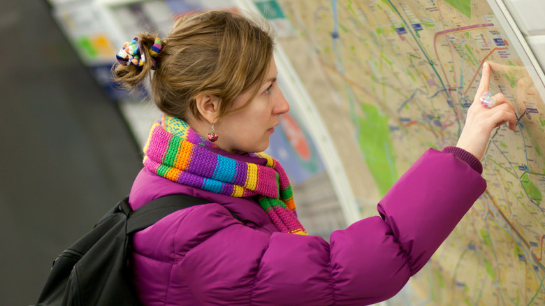 Woman in winter coat looks at a map inside a Paris Metro station