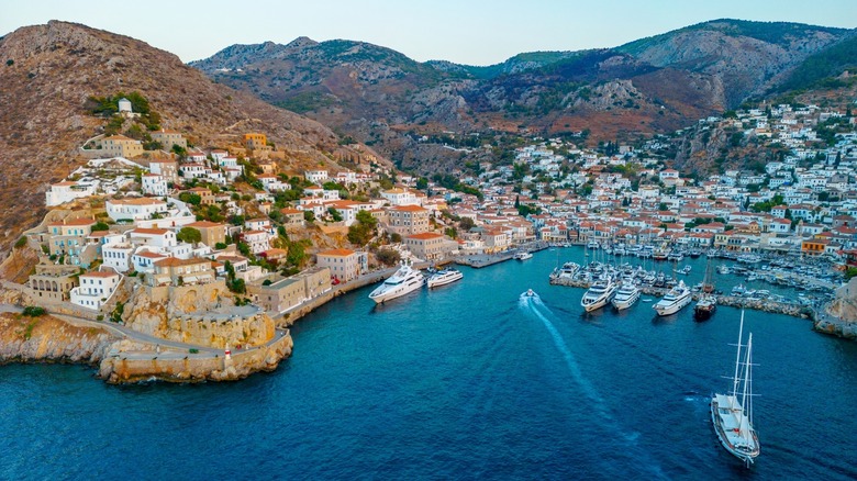 Panoramic view of a Greek island with houses along the hills and boats docked along the harbor