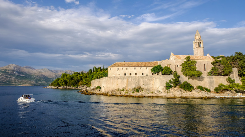 A monastery stands against the blue sea and sky in Lopud, Croatia