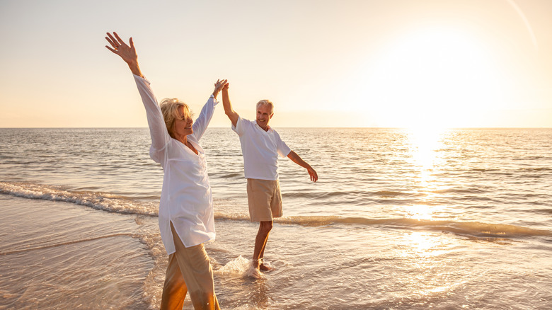 An elderly couple walking in celebration on the beach