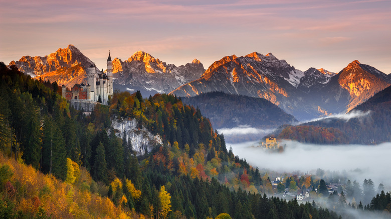 Landscape of fall foliage, mountains, and a castle in the Alps