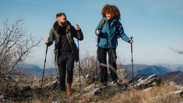 A smiling couple using hiking poles on a trail