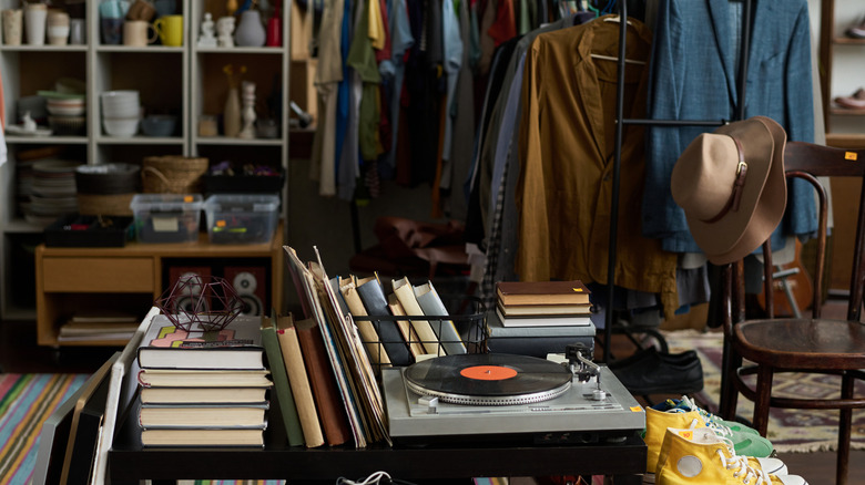 The inside of a thrift store with a record player, books, clothing, and other items