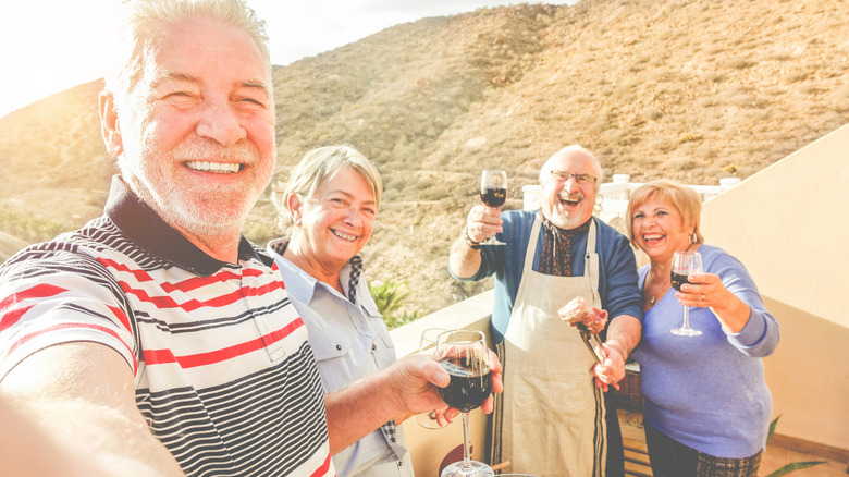 A group of seniors eating and drinking wine against a mountain backdrop
