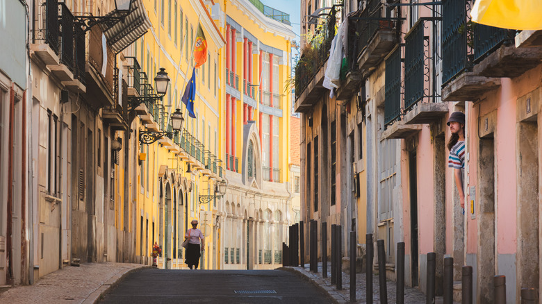 An elderly woman walking along a narrow street in Lisbon