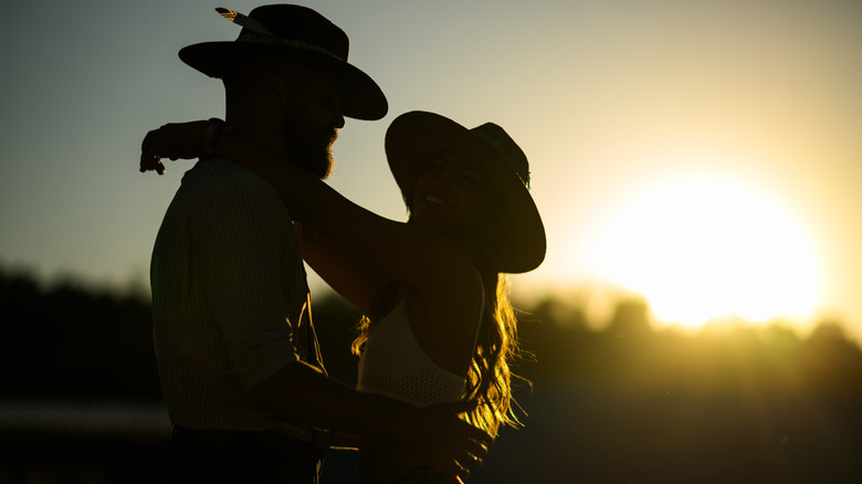 A couple in silhouette wearing cowboy hats against sunset in Texas