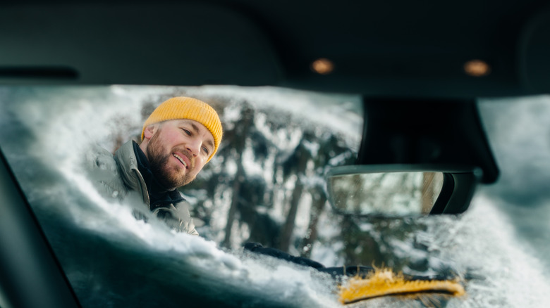 Man cleaning snow off a windshield