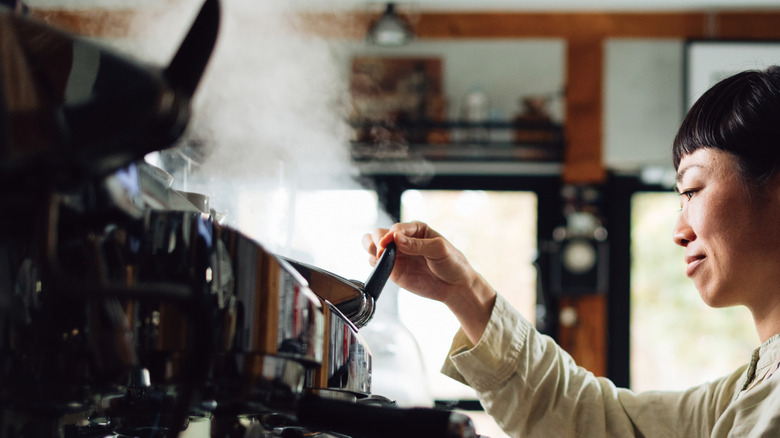 A barista steams milk at an espresso machine