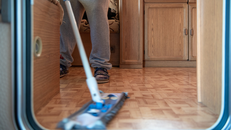 A person mopping an RV floor with a portable mop