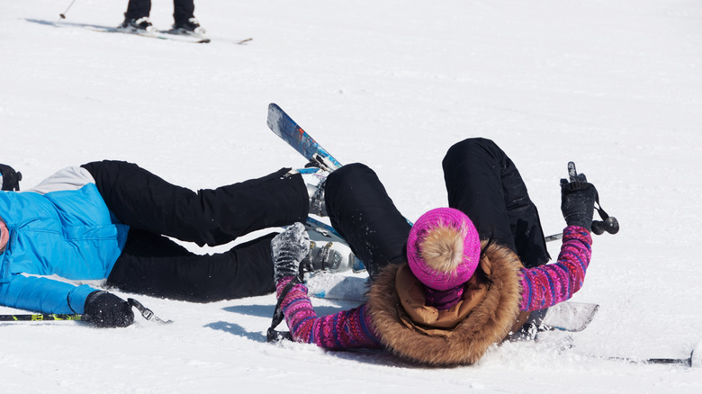 Two skiers on the ground after crashing on the ski slopes at a ski resort