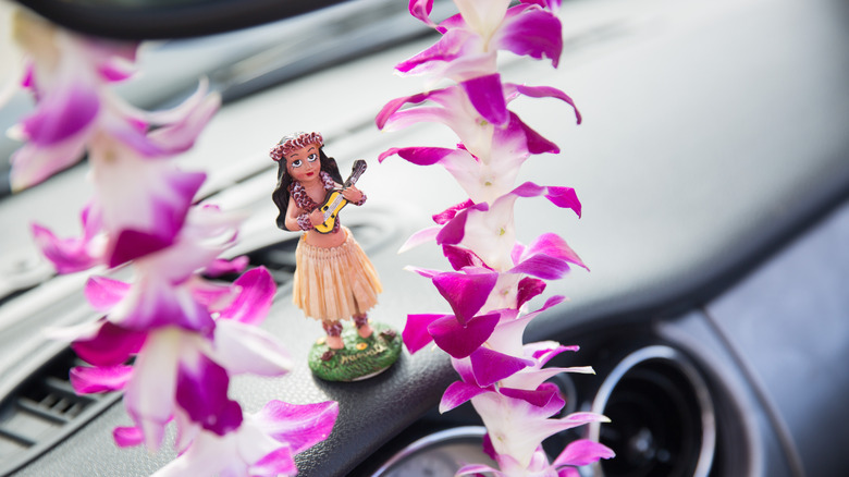 A Hawaii hula dancer dashboard ornament framed by an orchid lei