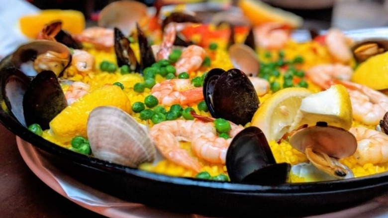 close up shot of bowl of rice, peas, and seafood