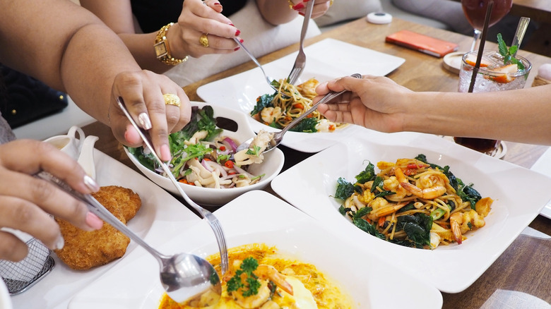 Diners serving themselves from sharing plates at a Thai restaurant.