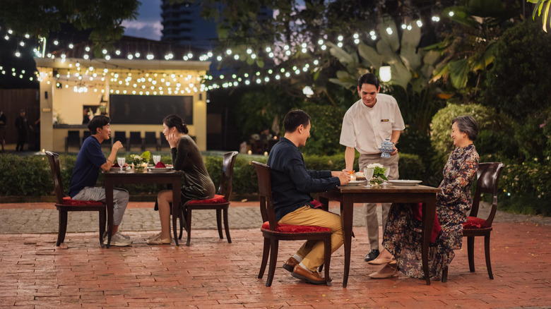 Two couples eat outdoor at a restaurant in Thailand.