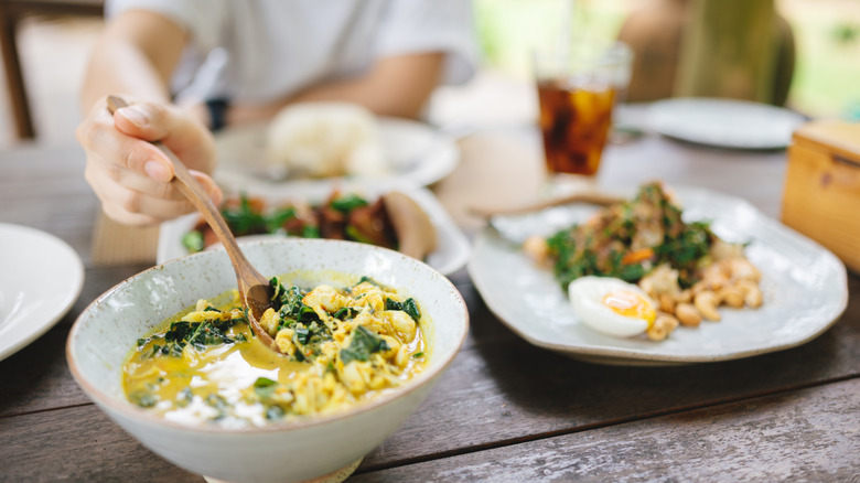 A man at a Southern Thai restaurant scoops a spoonful of curry onto his plate.
