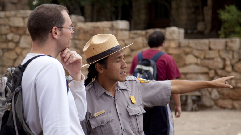 Ranger talking to park visitor and pointing to something