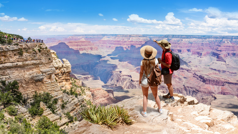 Two tourists standing at the edge of the South Rim of the Grand Canyon in Arizona