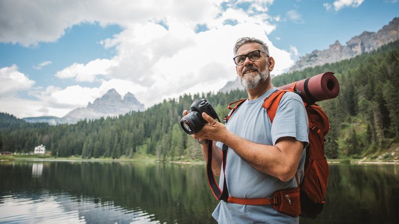 Hiker with a camera and backpack standing next to a river