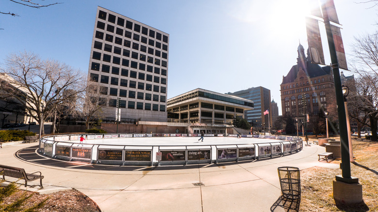 People ice skating on the rink at Red Arrow Park during the day