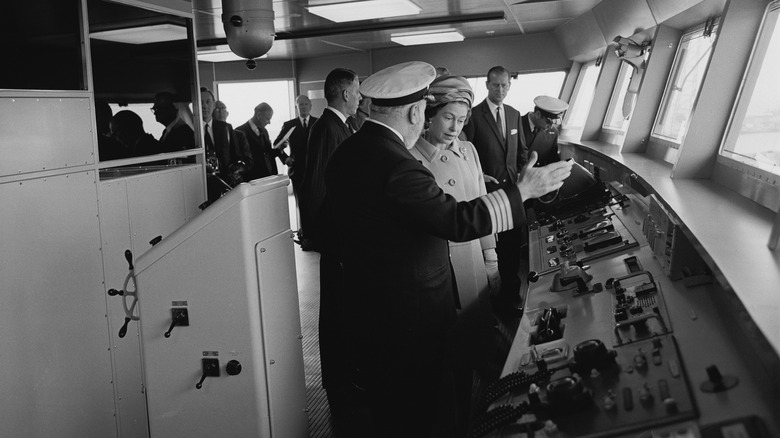 Woman talking to the captain on the bridge of a cruise ship in the 1960s