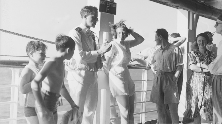 Passengers near the railing on a cruise ship in the 1940s, with kids in the foreground and adults in the background