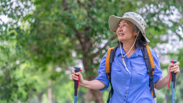 Cheerful older woman hiking with trekking poles