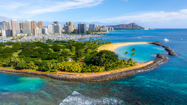 A coastal town with sandy beaches, blue water, and downtown buildings in the distance.