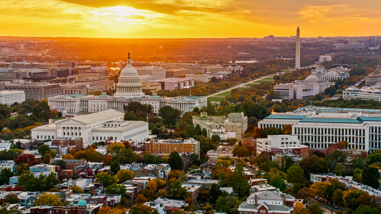 Helicopter shot of Capitol Hill in Washington, D.C. at sunset on a fall evening, looking over residential streets towards the U.S. Capitol Building, Supreme Court, and the National Mall