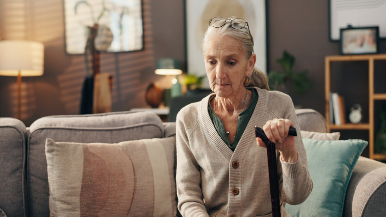 An old woman sitting on a sofa, alone and pensive