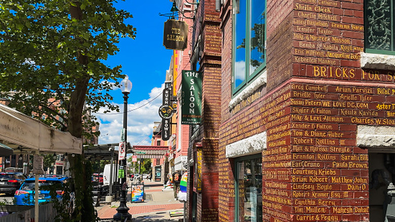 Engraved red bricks and hanging signs for The Saloon and nearby businesses along the historic U Street corridor in Washington, D.C.