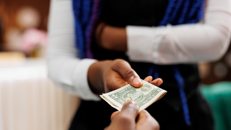 A hotel worker accepting a cash tip from a guest