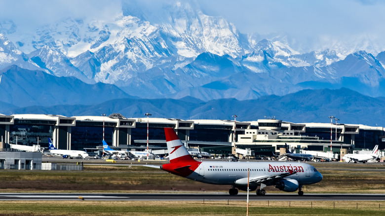 Austrian Airlines plane on runway with the Alps behind it