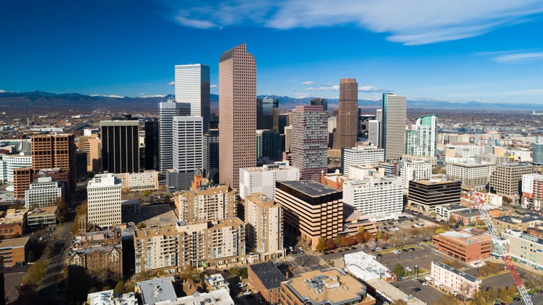 Aerial view of Denver's city center with high-rises, parks and the Rocky Mountains in the background.