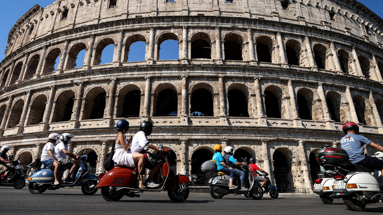 Vespa riders driving past the Colosseum in Rome