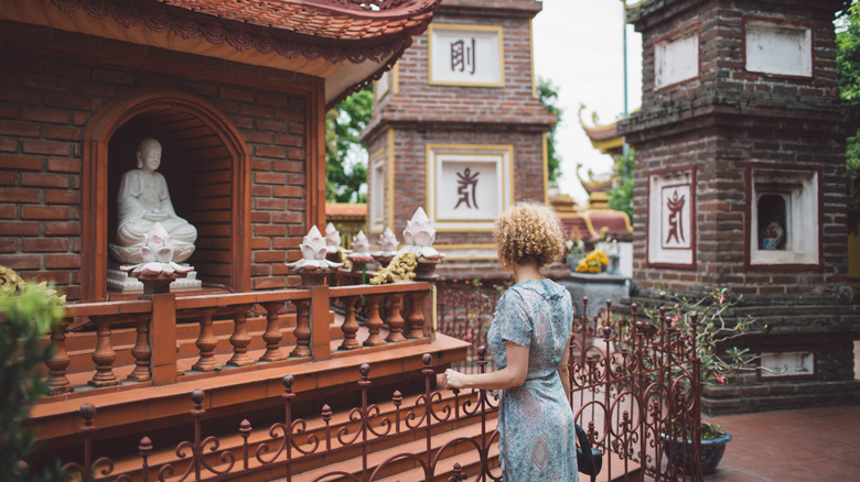 A tourist at a temple in Vietnam, wearing a dress with her shoulders and knees covered
