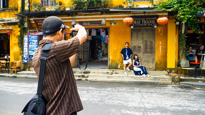 A photographer takes pictures of a couple in front of the yellow walls of Hoi An, Vietnam