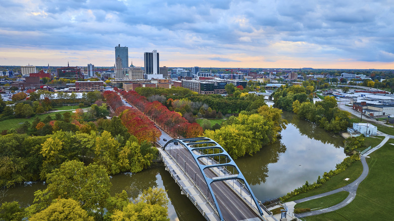 Golden hour captures autumn's vibrant hues in Fort Wayne, Indiana, featuring the modern Martin Luther King Bridge over a serene river with downtown skyline backdrop