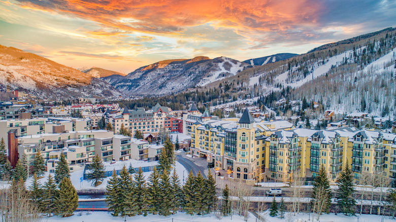 Ariel view of Vail Village in Colorado at twilight with a colorful sky and snowy mountains.