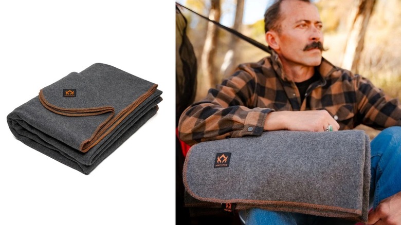 An outdoorsman warms up with a grey wool blanket in the woods