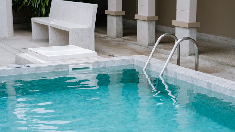 A ladder leading into a sparkling hotel swimming pool.