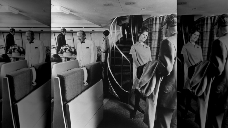 A flight attendant greets passengers in front of the staircase to the upper deck lounge