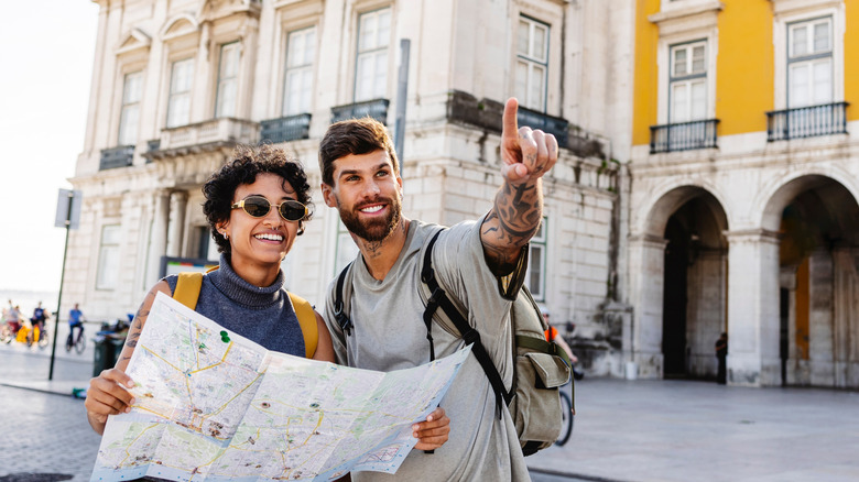 Two people pointing toward something looking at an itinerary