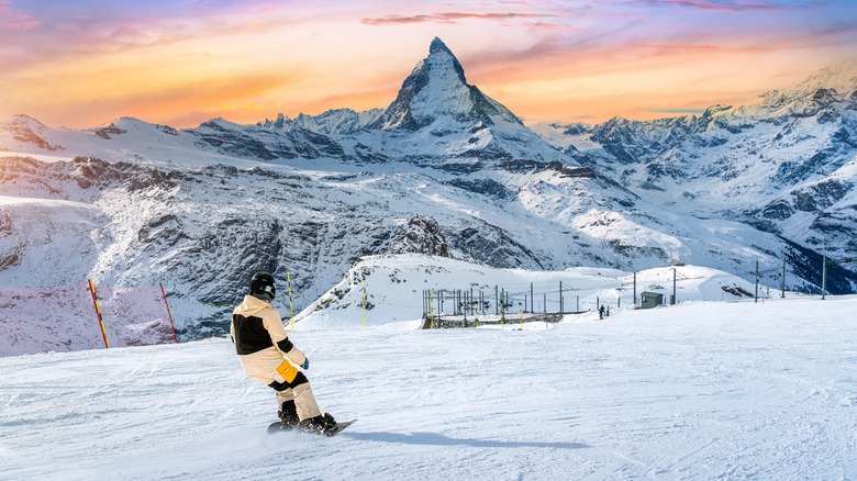 A snowboarder looks out over a massive peak