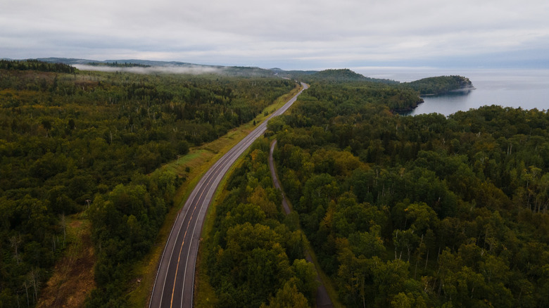 An aerial photo of Highway 61 in Minnesota surrounded by forest with lake Superior in the distance