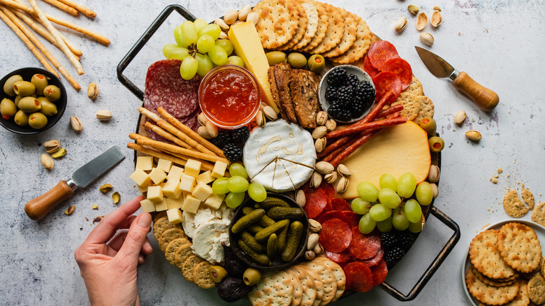 An overhead view of a charcuterie board with cheese, fruit, meats, and crackers