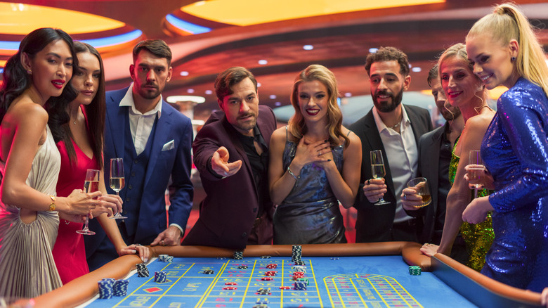 A group of young stylish men and women dressed in formal evening wear at a casino table